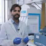 A MAN IN A LAB COAT IS TALKING AT THE CAMERA